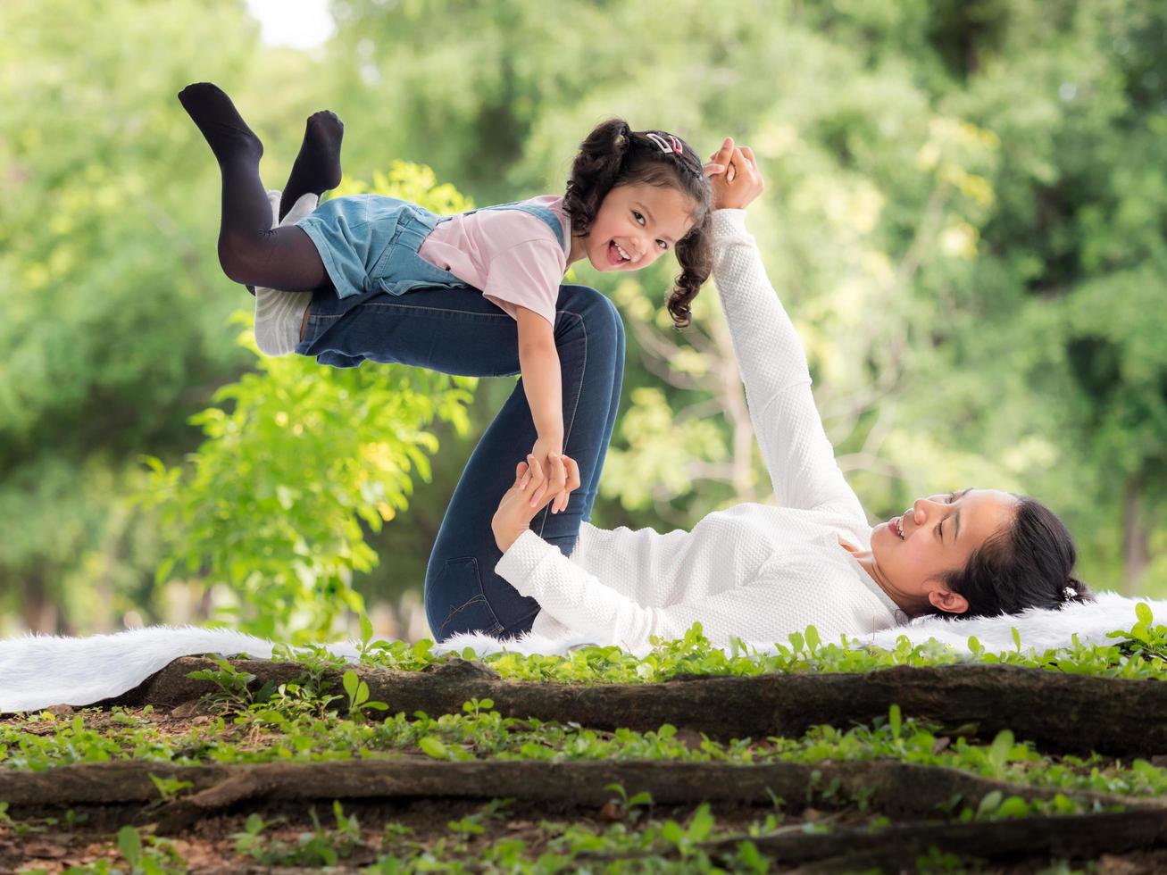 An Asian girl is lying on her mother's legs lying on the floor photo