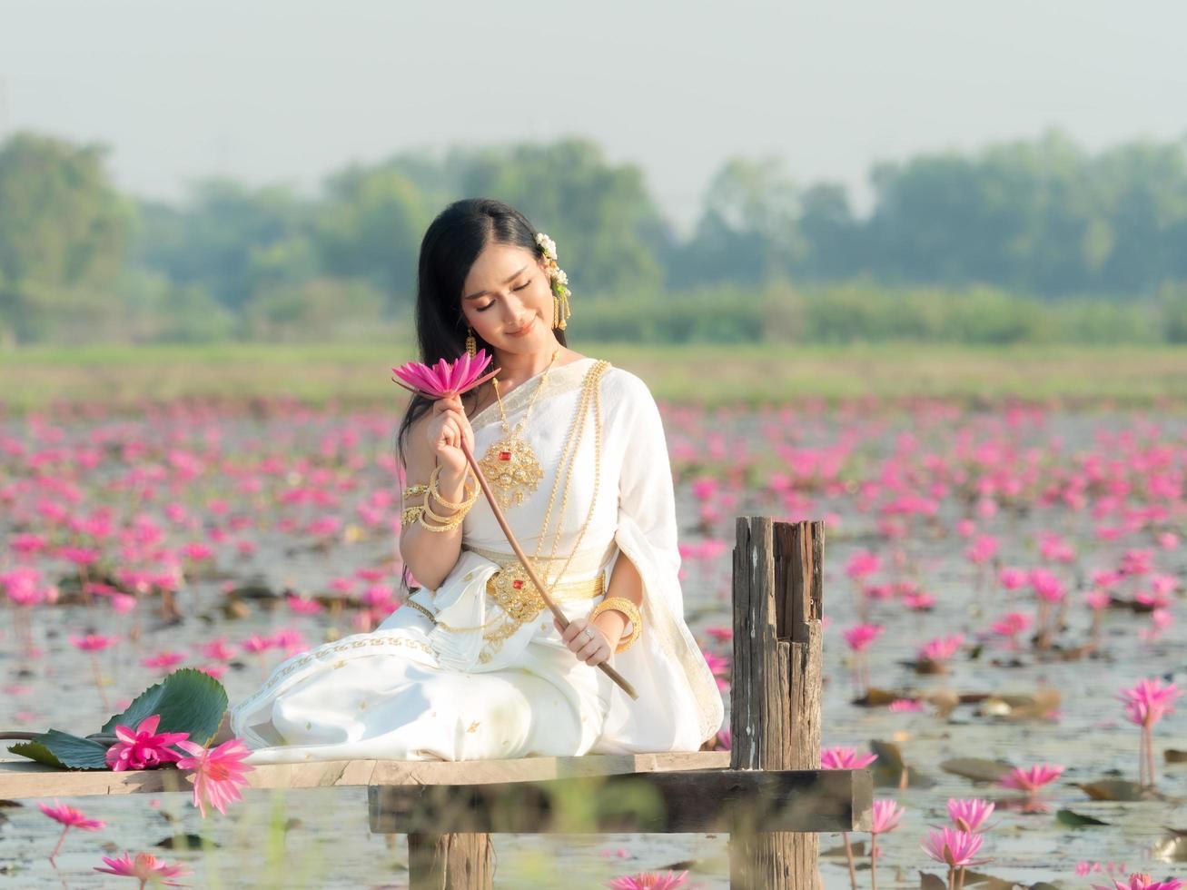 An elegant Thai woman wearing traditional Thai clothes  carrying lotus flowers leaf collected from a lotus field photo