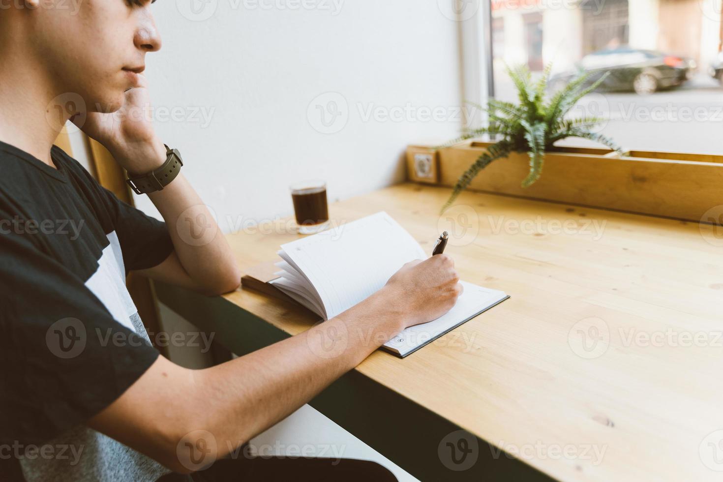 Young man writing information to notepad and speaking mobile phone, teenager in casual clothes plans a schedule photo