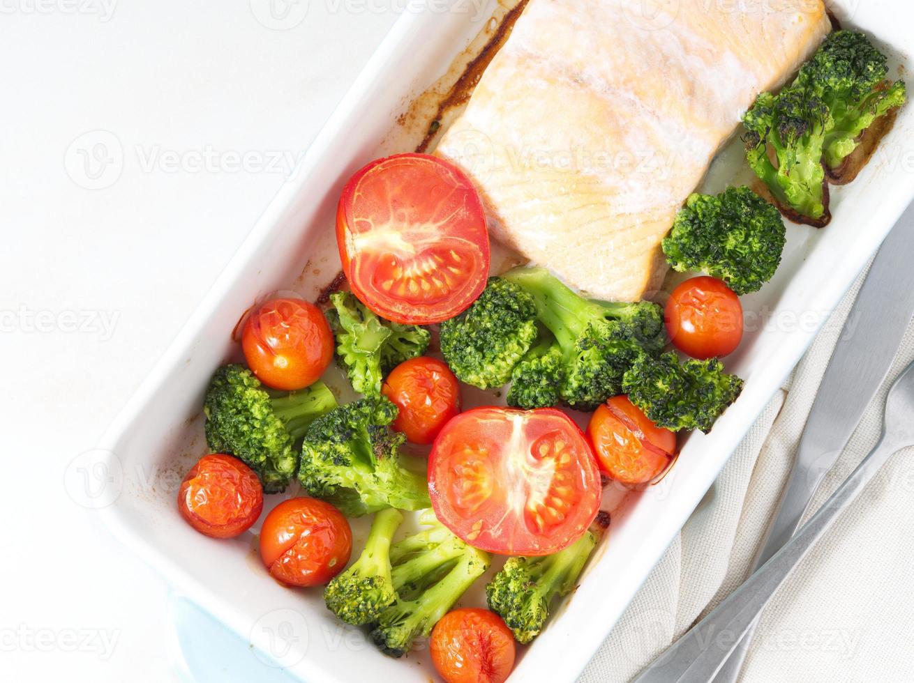 Fish salmon baked in oven with vegetables, broccoli. Healthy diet food, white marble backdrop, top view, close-up photo