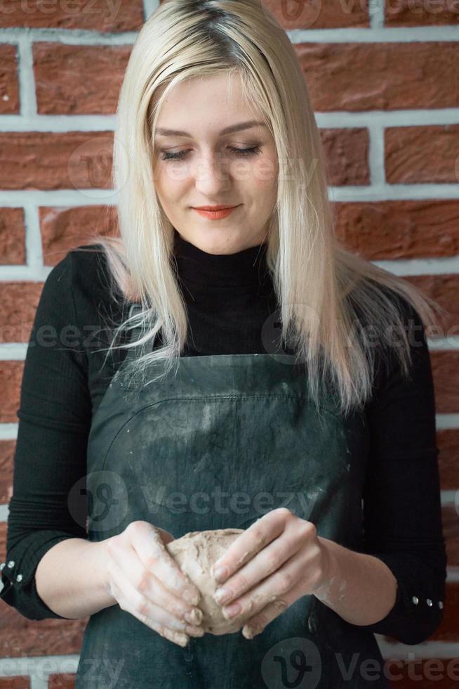 Smiling and happy woman making ceramic bowl in hand. Creative hobby concept. Earn extra money, side hustle, turning hobbies into cash, passion into job, vertical photo