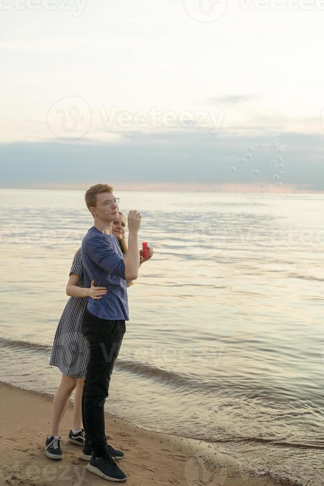 Teen Couple blowing soup bubbles on the beach photo