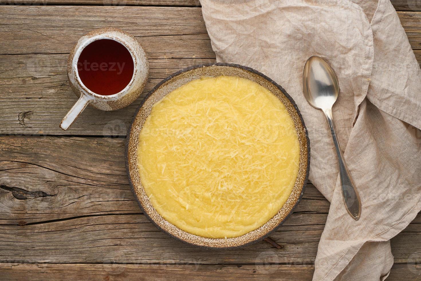 porridge polenta with cup tea, dark wood background, top view photo