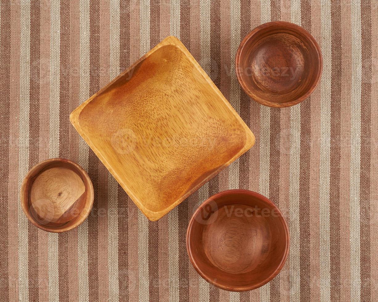 Wooden bowl on brown linen napkin, round and square shape photo