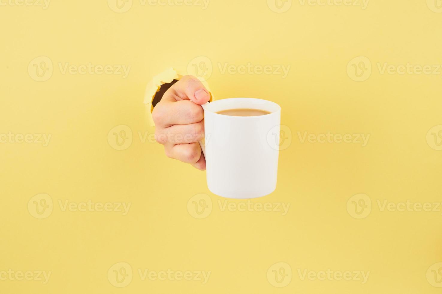 persona irreconocible sosteniendo una taza de té con fondo amarillo, espacio de copia cerrado foto