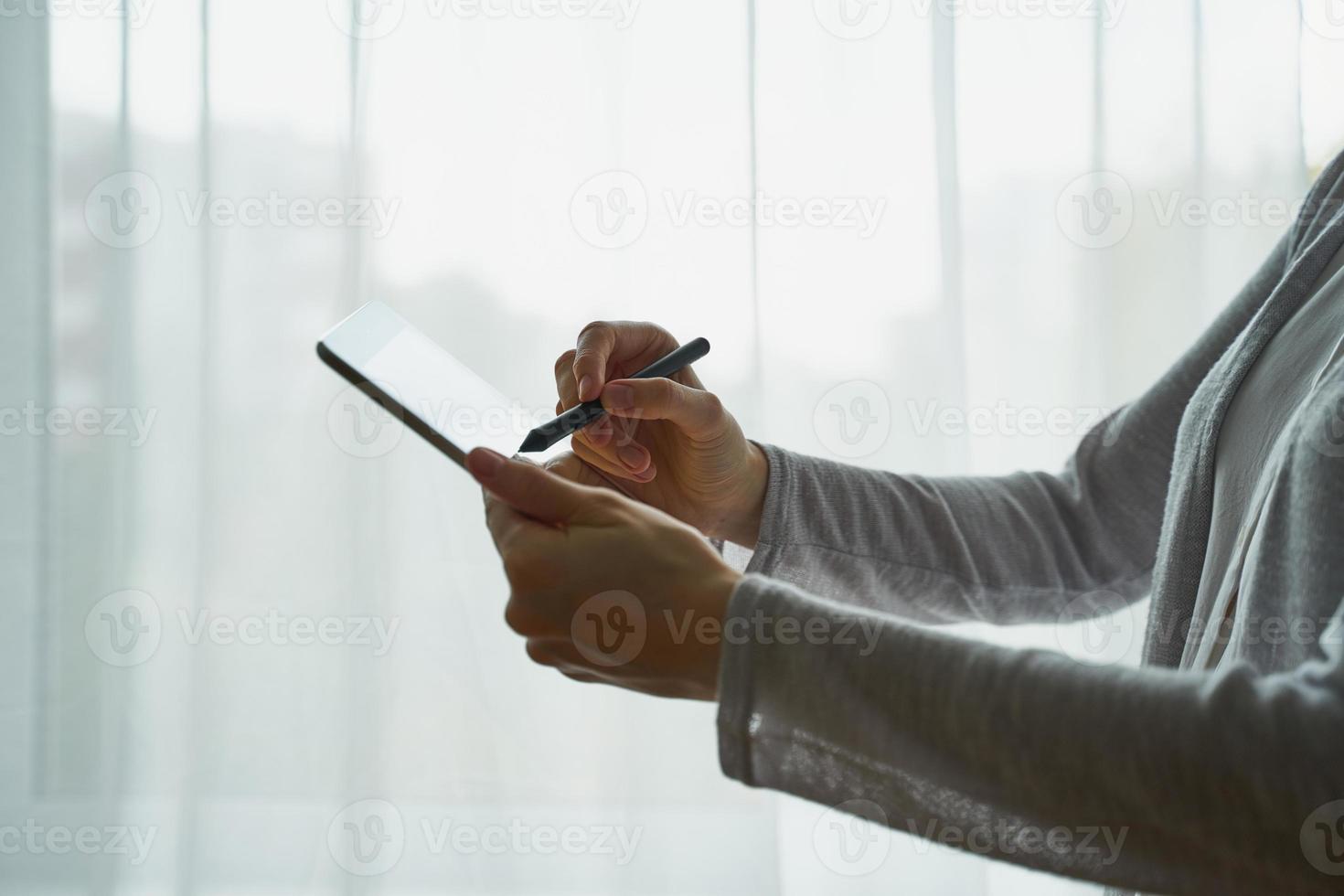 Woman holding tablet and writing on it, person with device side view closup photo
