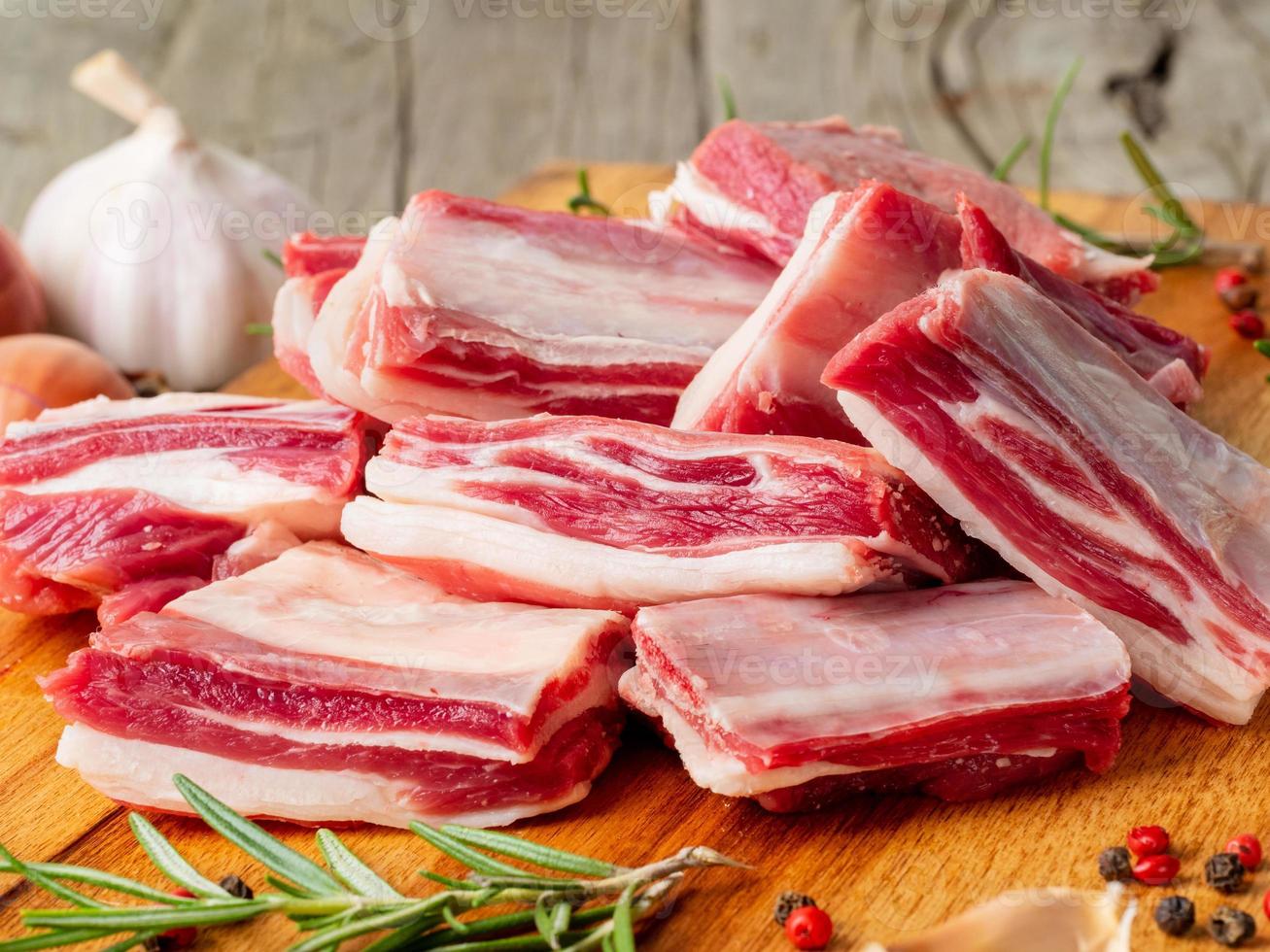 pequeños trozos de costillas de cordero crudas en una tabla de cortar de madera foto