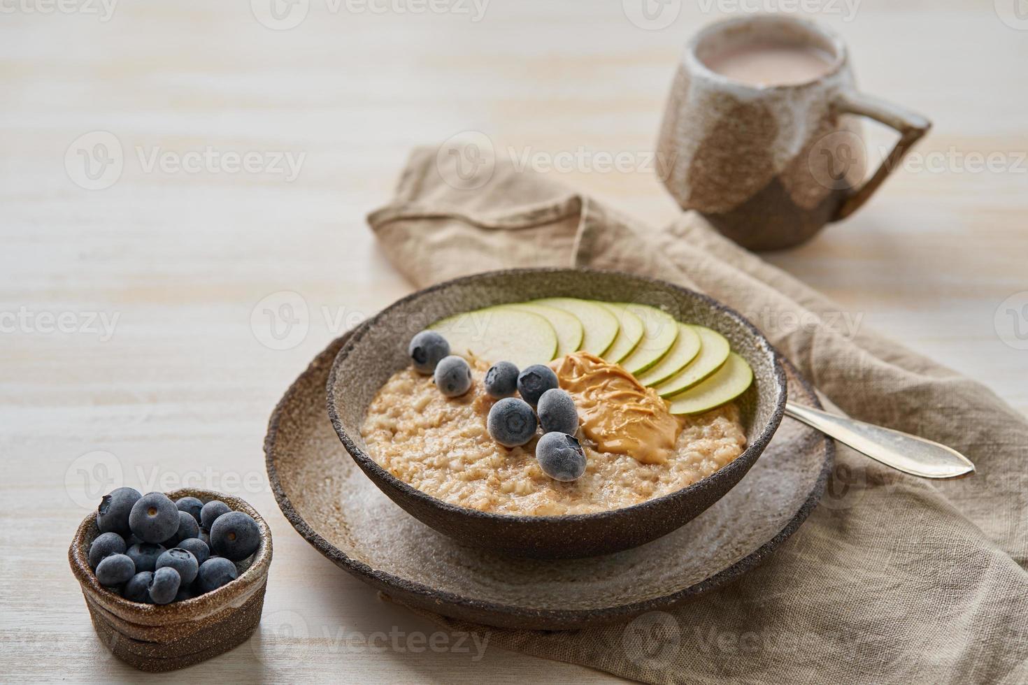 Oatmeal, healthy porridge in large bowl with fruits and berry for breakfast, cup of cocoa. Top view photo