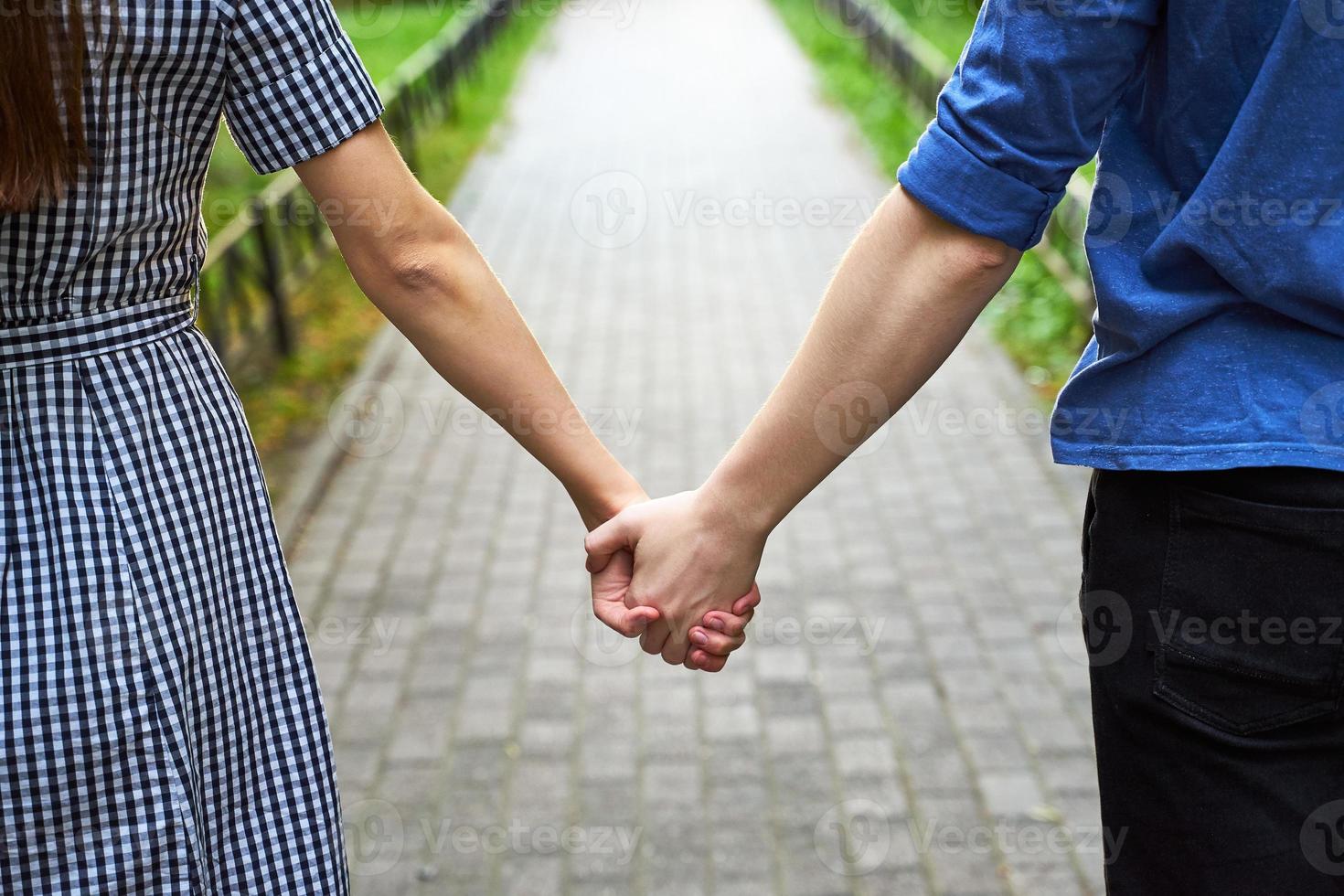 Closeup of loving couple holding hands while walking in the park photo