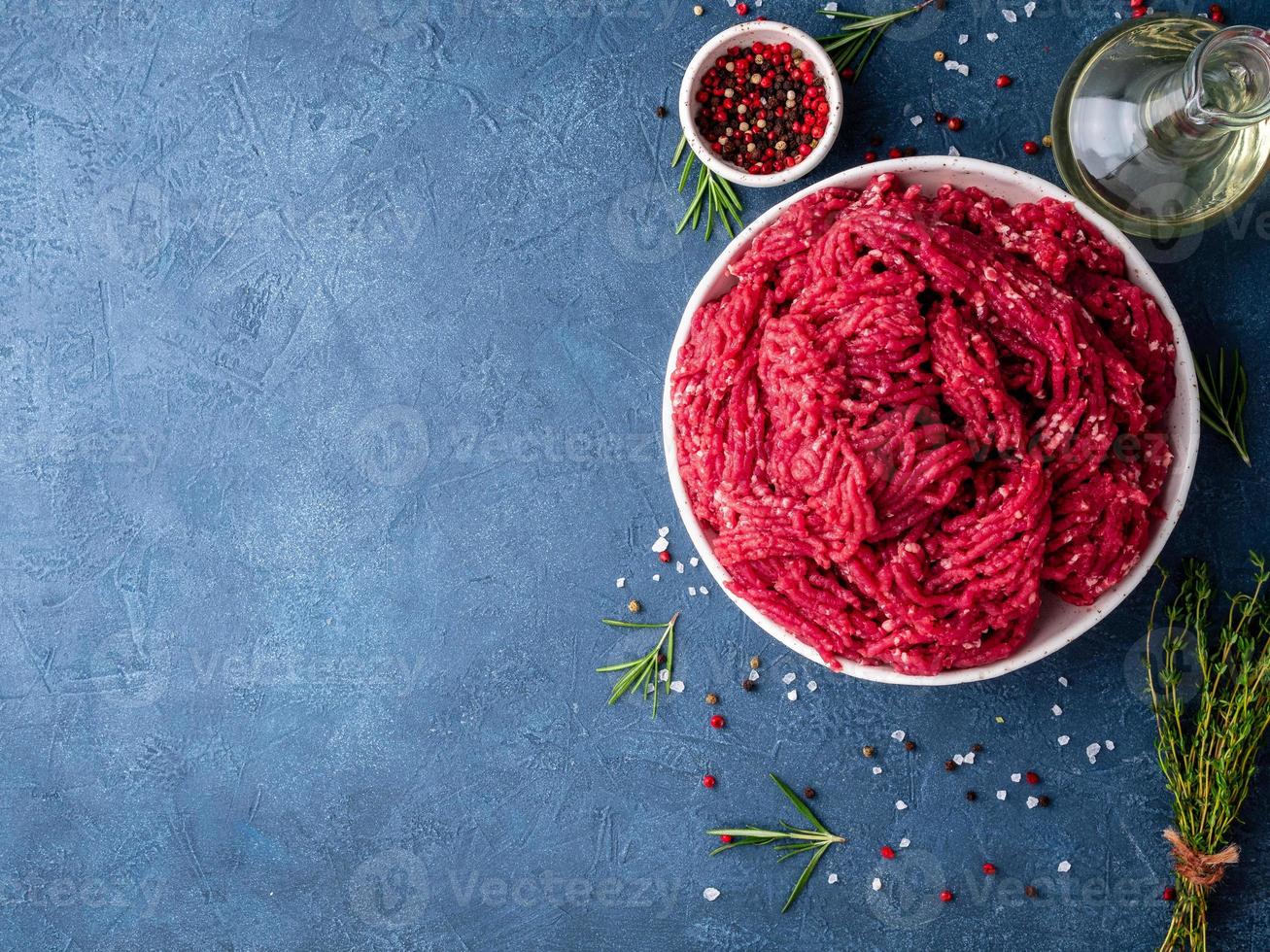 carne picada, carne molida con ingredientes para cocinar en azul oscuro foto