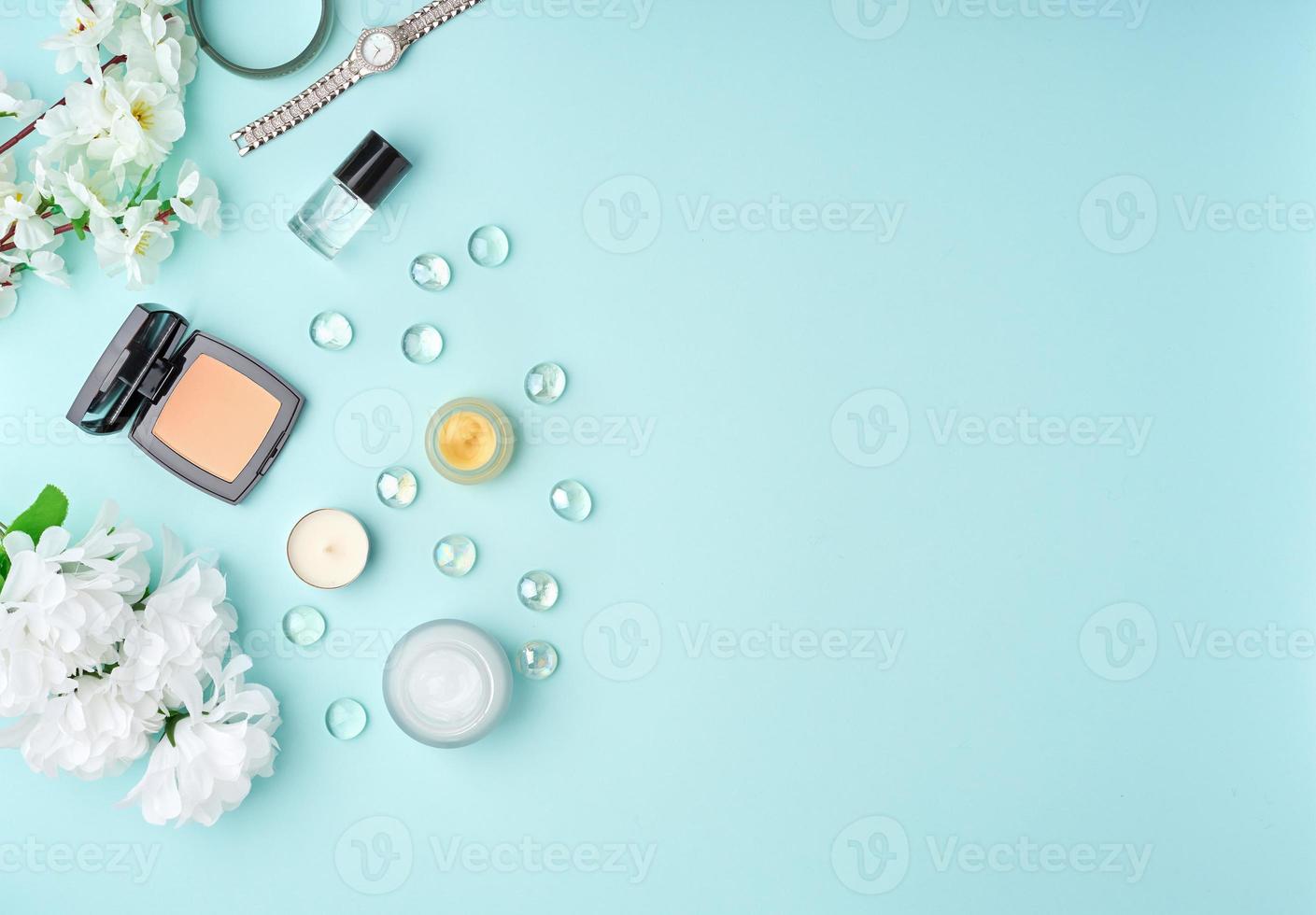accesorios planos para mujer con cosméticos, crema facial, bolso, flores en una mesa azul pastel. foto