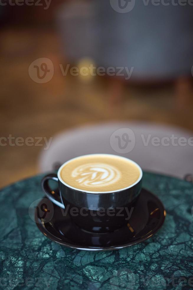 una taza de capuchino con espuma sobre una mesa de mármol en un pequeño y acogedor café. beber foto