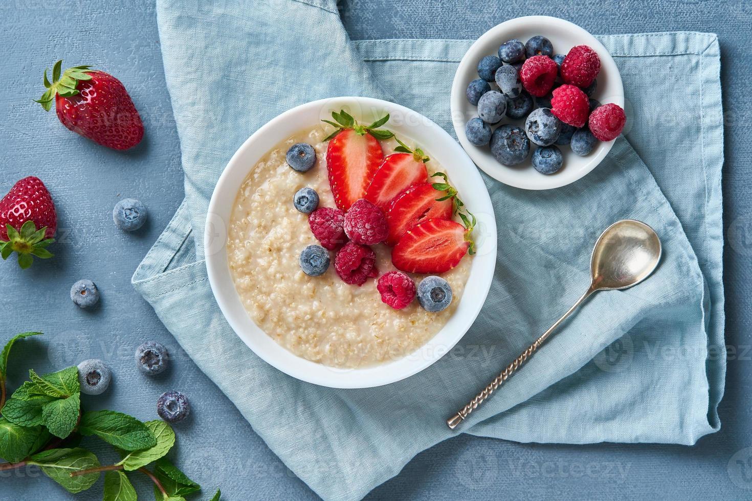 Oatmeal with blueberry, strawberry, raspberry on blue dark background. photo