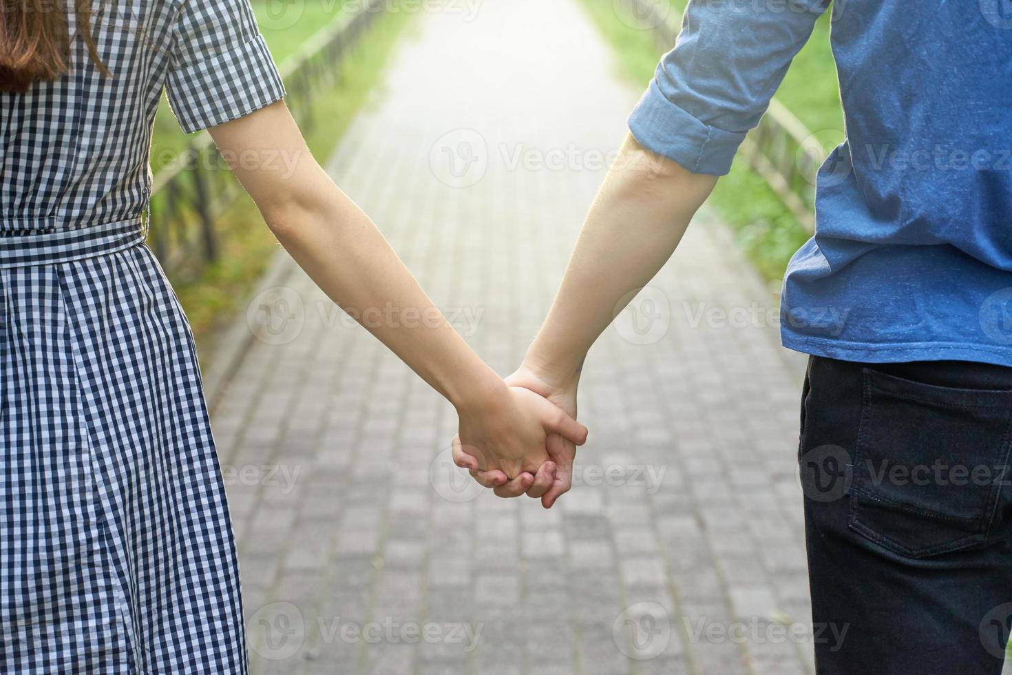 Couple holding hands while walking in the park closeup photo