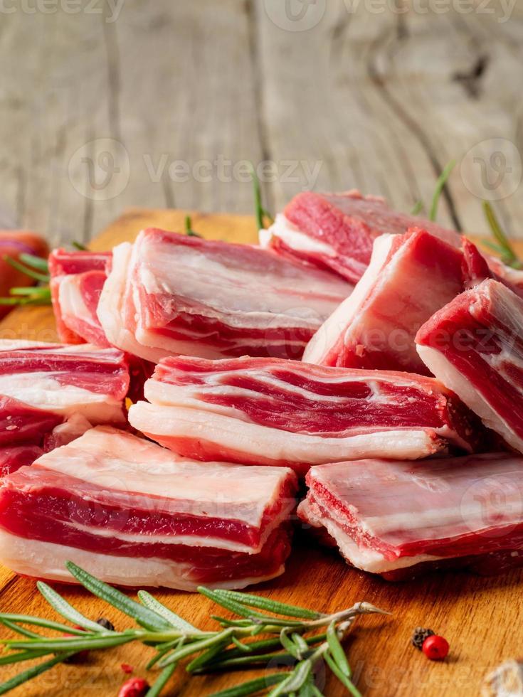 pequeños trozos de costillas de cordero crudas en una tabla de cortar de madera foto