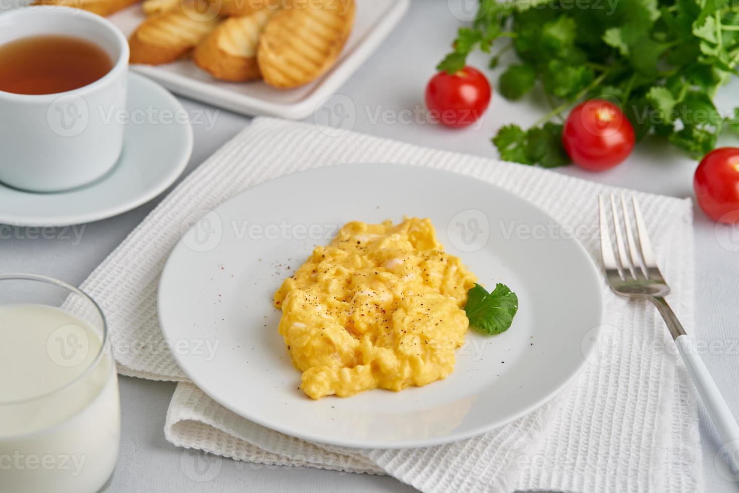 Scrambled eggs, omelet, side view. Breakfast with pan-fried eggs, glass of milk photo