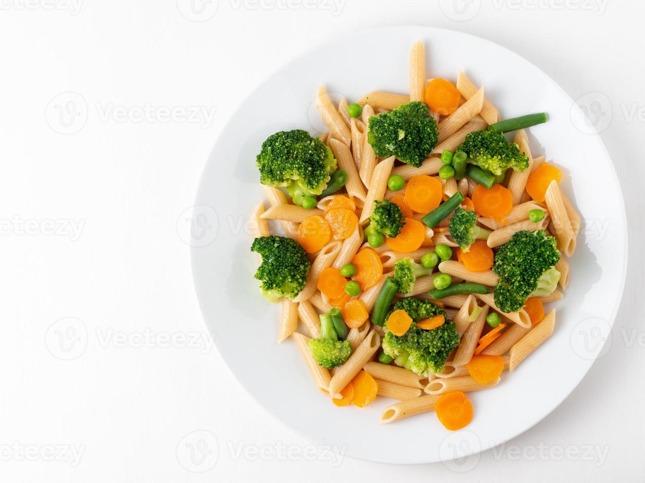 Whole wheat pasta Penne with broccoli, carrots, green peas. Copy space, top view. Diet menu photo