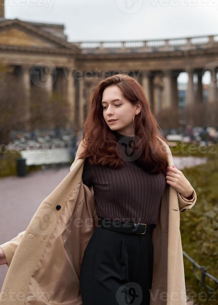 Beautiful funny naughty stylish fashionable happy girl dancing on streets of St. Petersburg city. Charming smiling woman with long dark hair, vertical photo