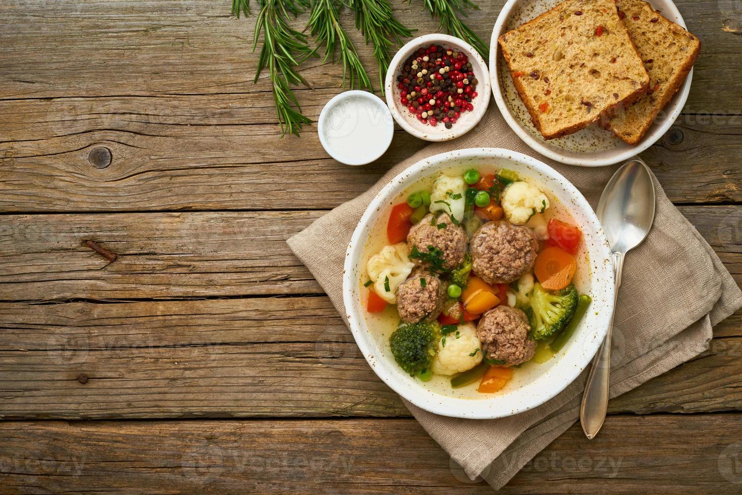 meatballs soup in white plate on old wooden rustic grey table, top view photo