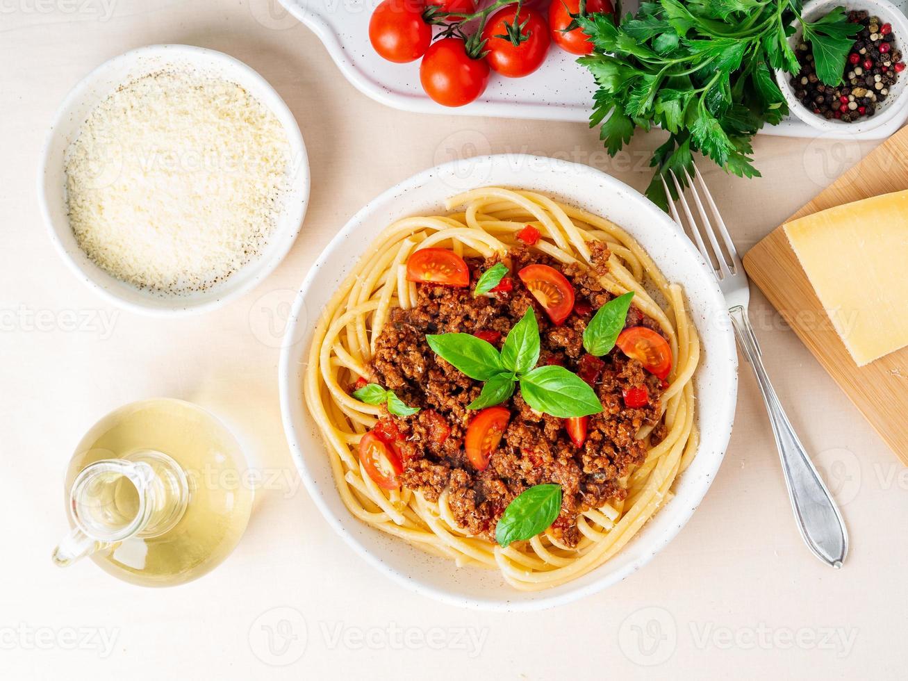 pasta bolognese with tomato sauce, ground minced beef, basil leaves on background photo