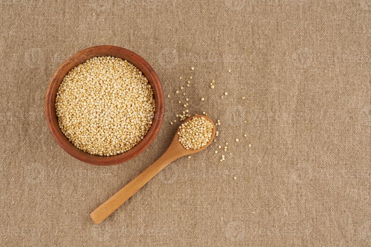 quinoa seed grain in wooden bowl and spoon on linen napkin, close up photo