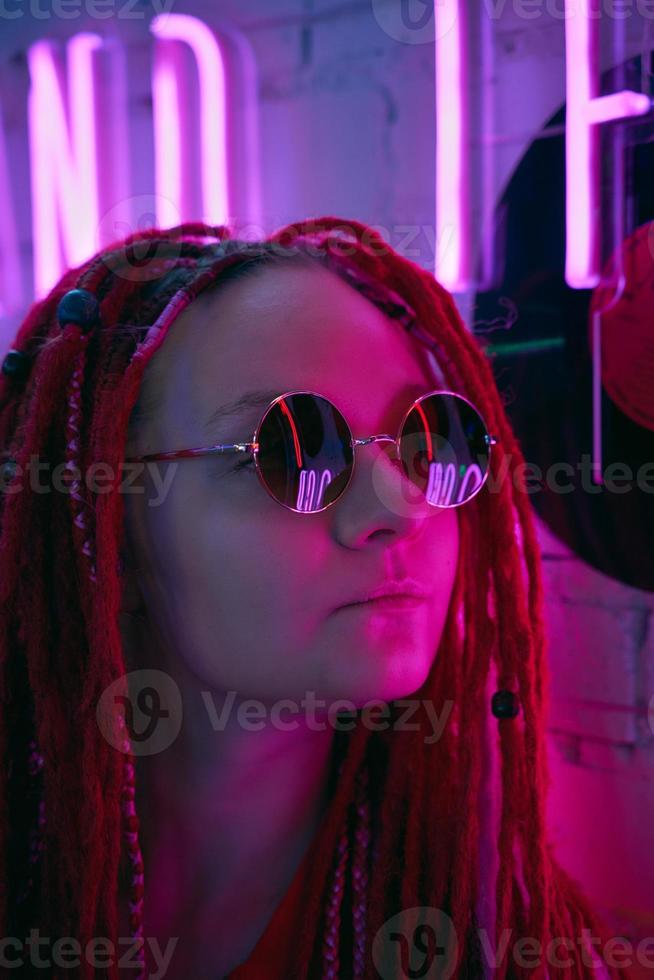 chica con luces de neón, hermosa mujer con gafas de sol, con el pelo rosa, con coletas con rastas foto