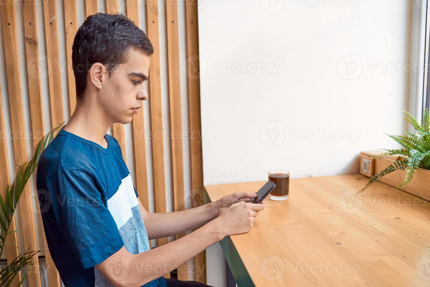 Young adult looking at the phone, sitting in a cafe. Digital age. People communicate in chat. photo