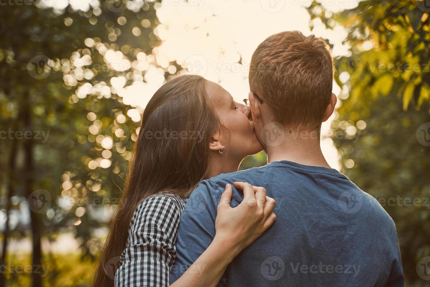 chica besando a chico en la mejilla en el parque, concepto de amor adolescente foto