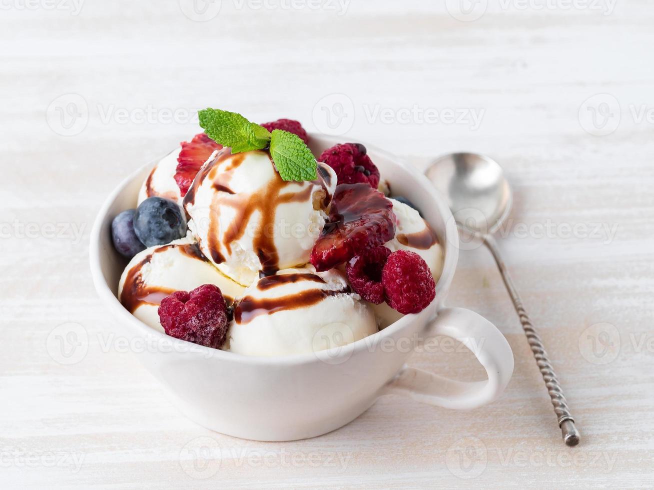 Balls of vanilla ice cream in mug with raspberry and blueberries photo