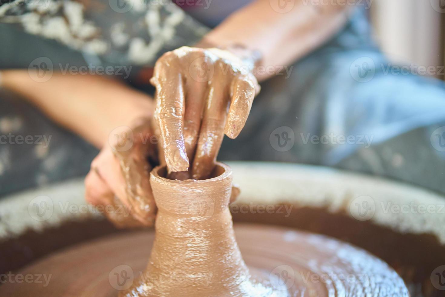 Woman making ceramic pottery on wheel, hands close-up, creation of ceramic ware photo