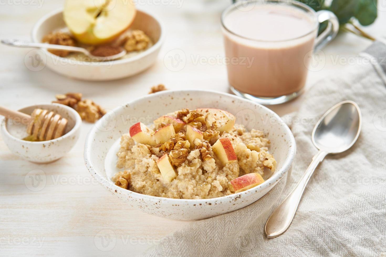 Oatmeal with apple, walnuts and cup of cocoa on white wooden light background photo