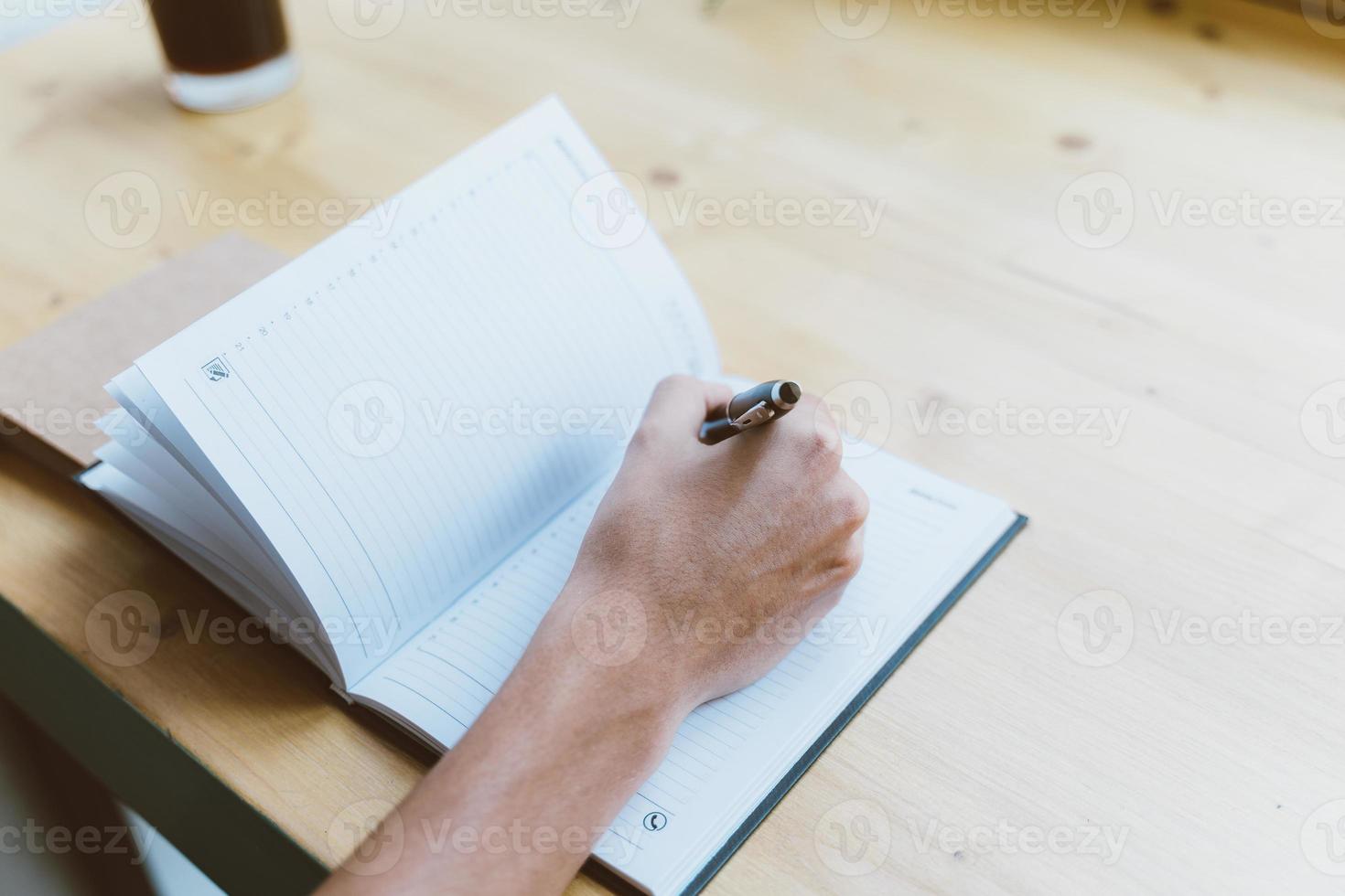 Young man, unrecognizable person writing information to notepad, teenager in casual clothes plans a schedule, daily, to-do list photo