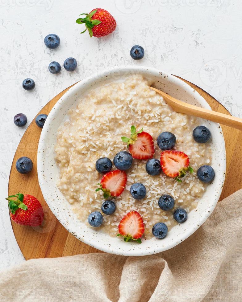 gachas de avena rústicas con bayas, dieta dash, en la vista superior de fondo de madera blanca foto