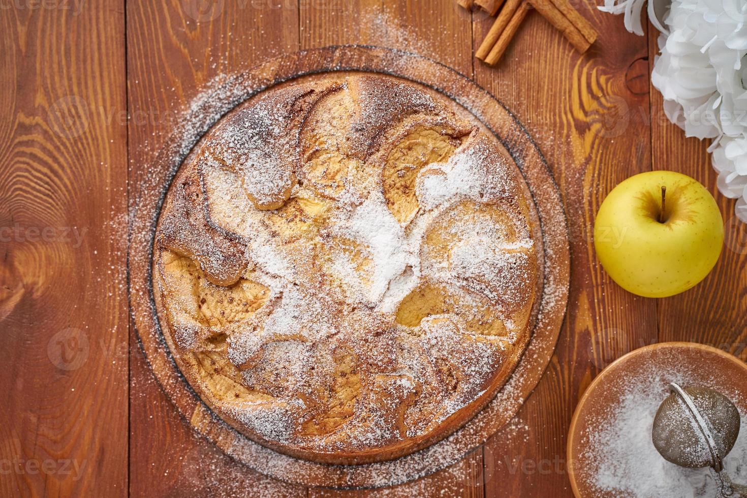 Apple french cake with apples, cinnamon on dark wooden kitchen table, top view photo