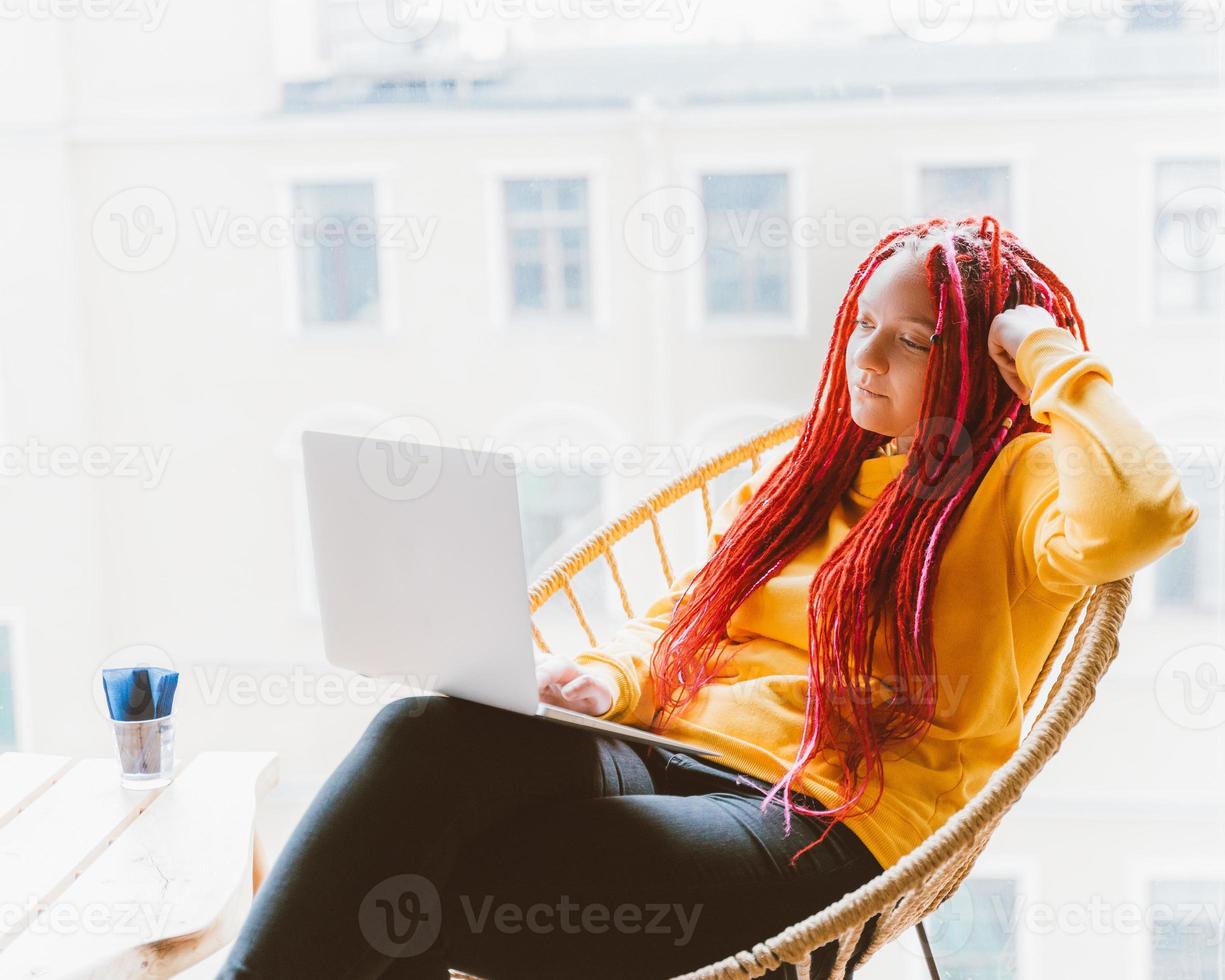 concepto de nómada digital. chica independiente que trabaja de forma remota en una computadora portátil en un café, coworking. foto