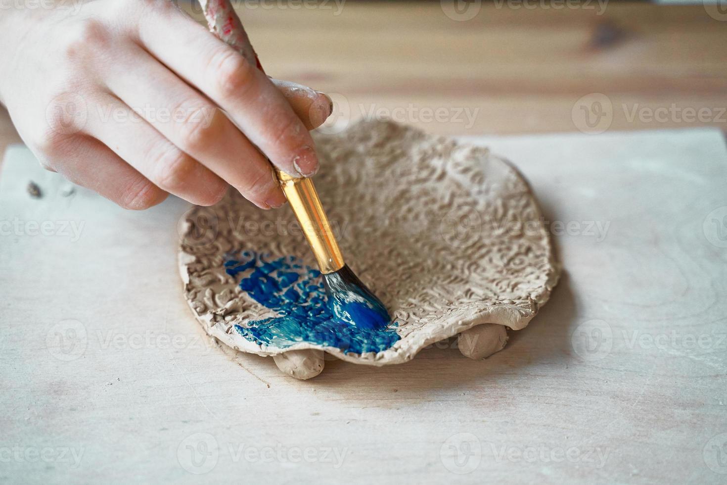 Unrecognised Woman making pattern on ceramic plate, hands close-up photo