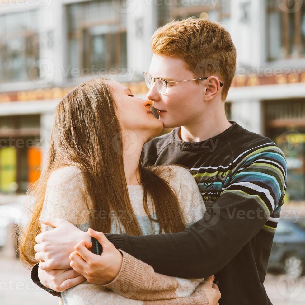The redhead boy looks tenderly at girl and kiss. Concept of teenage love and first kiss, love, relationship, couple photo