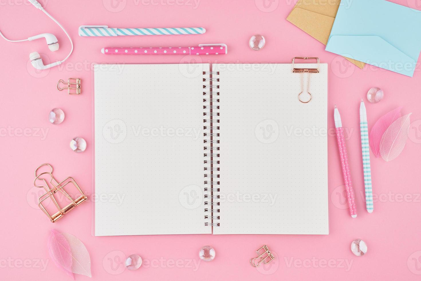 página de bloc de notas en blanco en el diario de viñetas en el escritorio de oficina rosa brillante. vista superior de la mesa luminosa moderna con cuaderno, papelería. maqueta, espacio de copia, concepto de diario foto