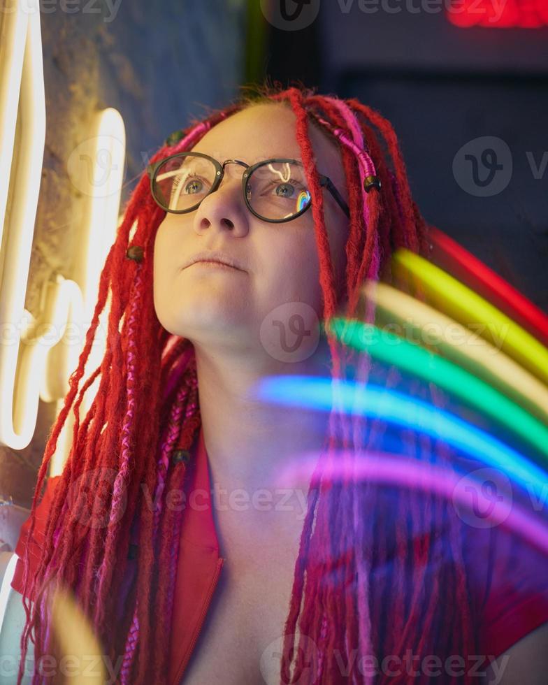 Girl in neon lights, beautiful woman in sunglasses, with pink hair, with dreadlocks pigtails photo