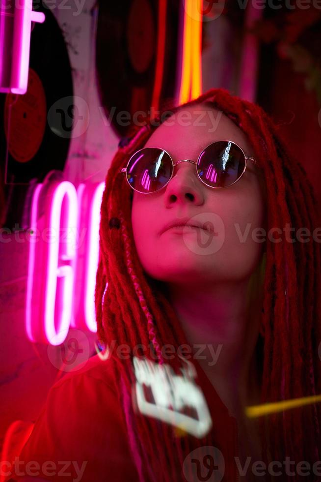 chica con luces de neón, hermosa mujer con gafas de sol, con el pelo rosa, con coletas con rastas foto