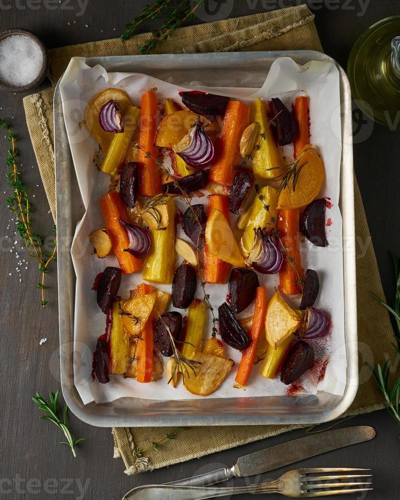 Colorful roasted vegetables on tray with parchment. Mix of carrots, beets, turnips, photo