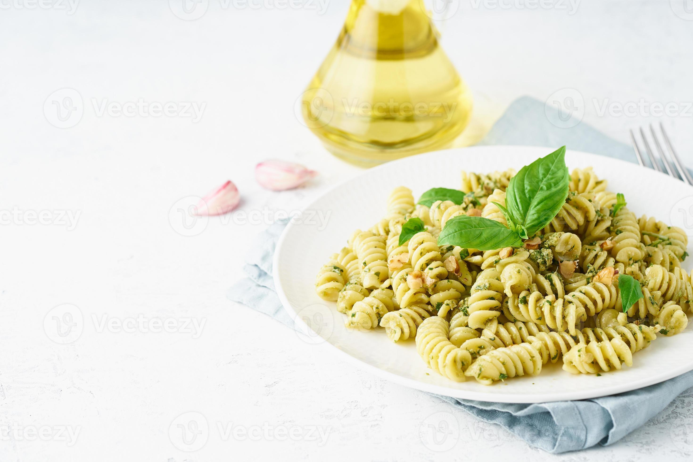 fusili pasta with basil pesto and herbs, italian cuisine, gray stone