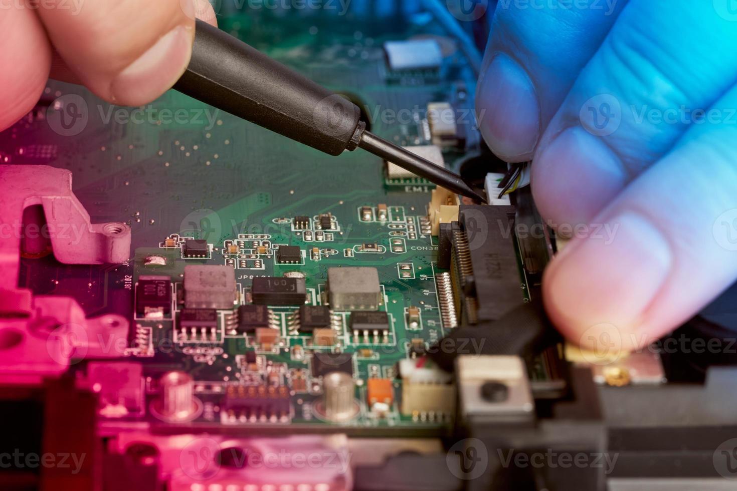 el hombre repara la computadora. un ingeniero de servicio en camisa repara una computadora portátil, foto