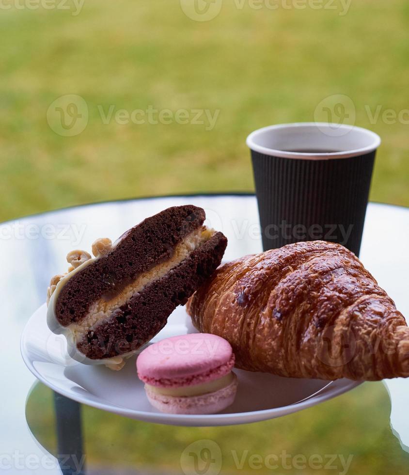Breakfast with croissant and dessert, coffee or tea in plastic mug, in the village photo
