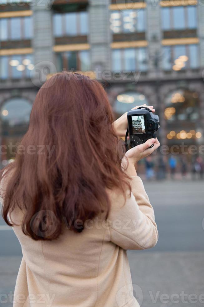 Unrecognizable person standing with his back turned and photographs sights, woman with long thick dark hair, tourist in center of St. Petersburg. Focus on camera photo