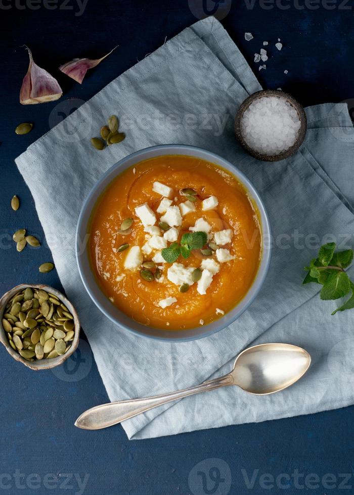 sopa de crema de calabaza con queso feta, comida casera de otoño, fondo azul oscuro foto