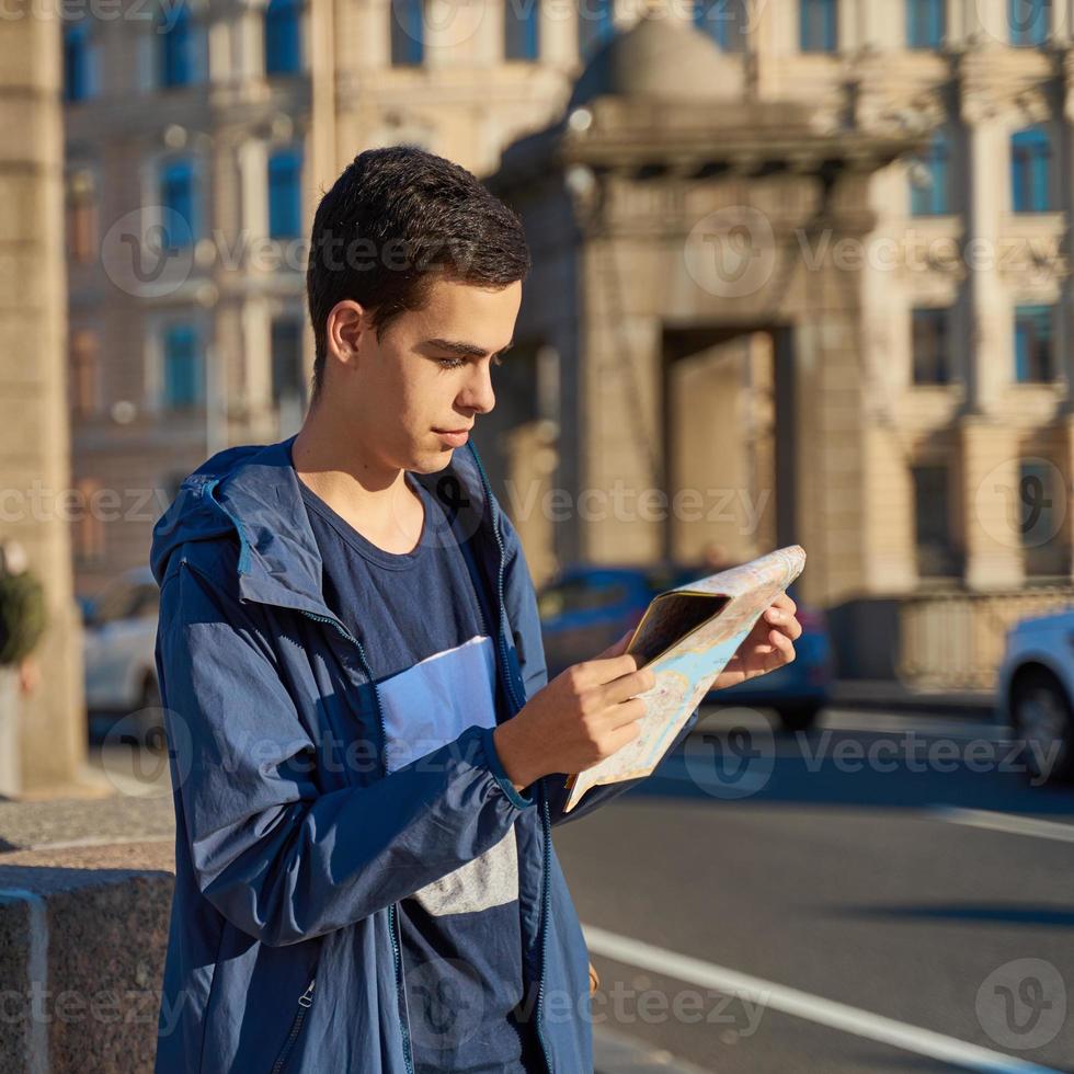 Young man standing on street of big city and looking at guide, a tourist in St. Petersburg looking for for attractions photo