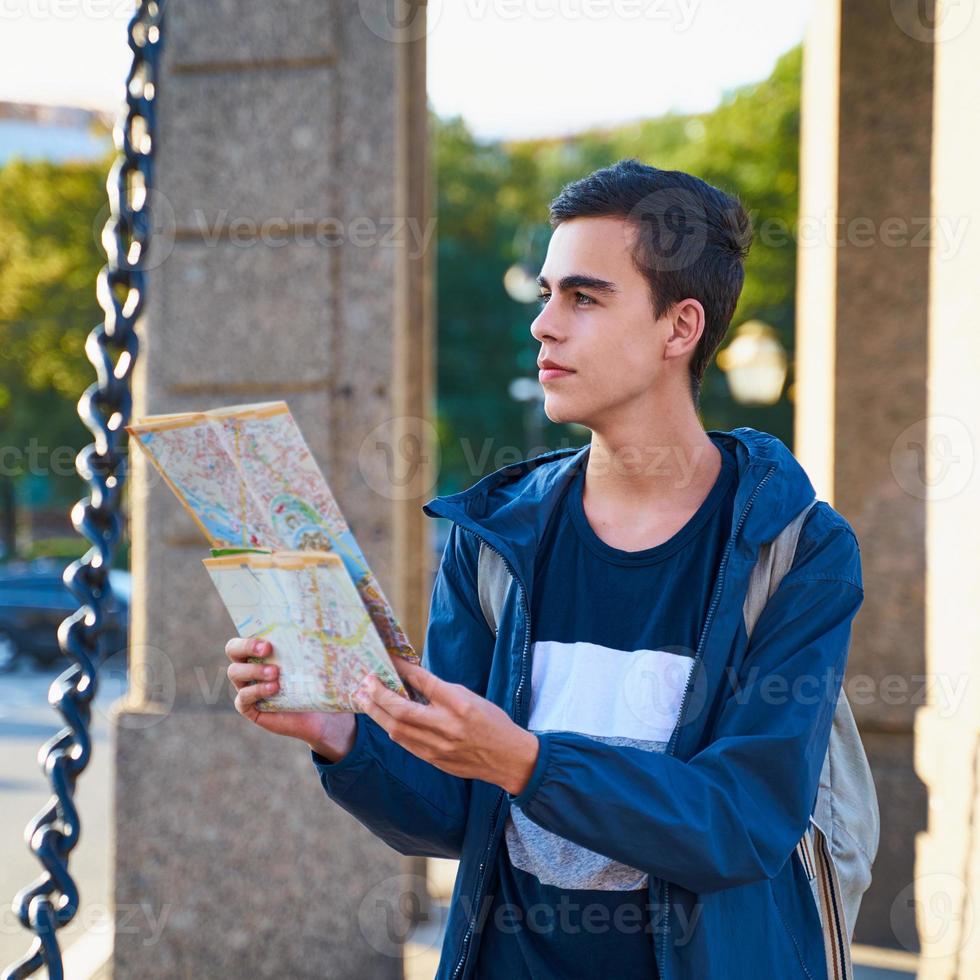 Young man standing on street of big city and looking at guide, a tourist in St. Petersburg looking for a route photo