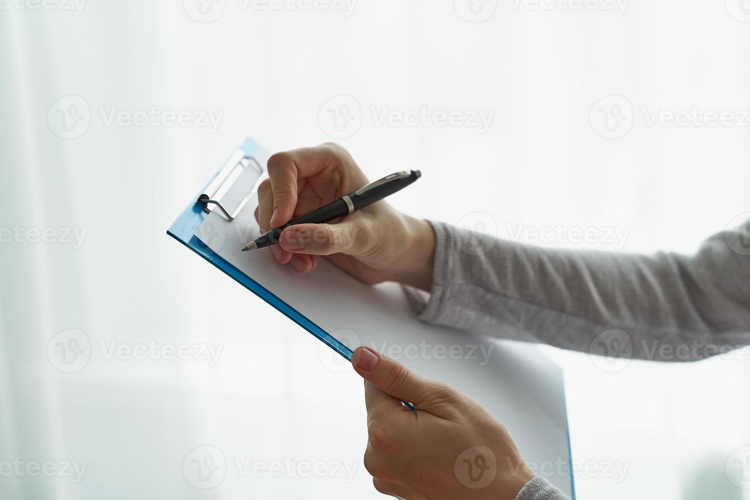 Woman holding clipboard, concept of office work or studying student side view closeup photo