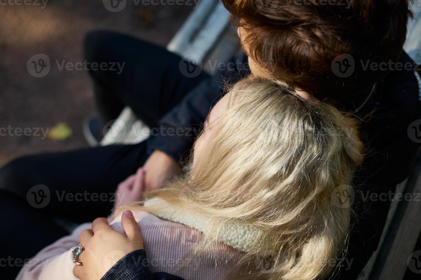 loving couple of men and women sitting on a bench, resting in the rays of the autumn sun photo